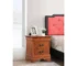 Oak wood nightstand with two drawers in a cozy bedroom setting