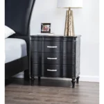 Black solid wood nightstand with curved front and turned legs in a bedroom setting