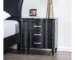 Black wood nightstand with curved front and turned legs in a modern bedroom setting