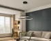 Modern LED pendant light with black metal frame, hanging over a wooden dining table in a bright living room with soft