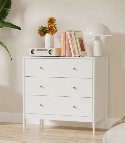 Modern white 3 drawer dresser with gold-tone knobs and lacquer finish in a bedroom setting