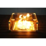 Gray wicker outdoor gas fire pit table with ice bucket and glass wind guard on patio