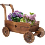 Wooden wagon planter box with four wheels, filled with flowers, on a patio.