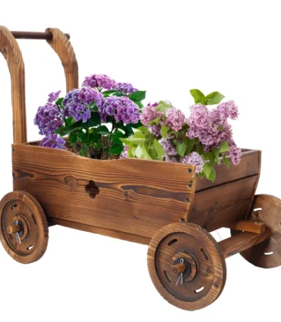 Wooden wagon planter box with four wheels, filled with flowers, on a patio.
