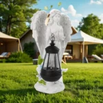 Detailed view of angel figurine's face and feathered wings, lantern lit, against brick wall.