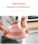 Elegant dinnerware set with gilt rim pink porcelain plates, bowls, mugs, and cutlery on a table