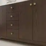 Detailed view of the plywood cabinet doors with brushed nickel handles and the floor-standing base of the bathroom