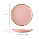 Elegant dinnerware set with gilt rim pink porcelain plates, bowls, mugs, and cutlery on a table