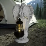 Angel lantern statue illuminated at dusk, casting soft light on garden lawn.