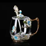 Elegant crystal glass tea mug with enamel floral design and handgrip on a wooden table