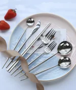Elegant stainless steel flatware set with forks, spoons, and knives arranged on a wooden table