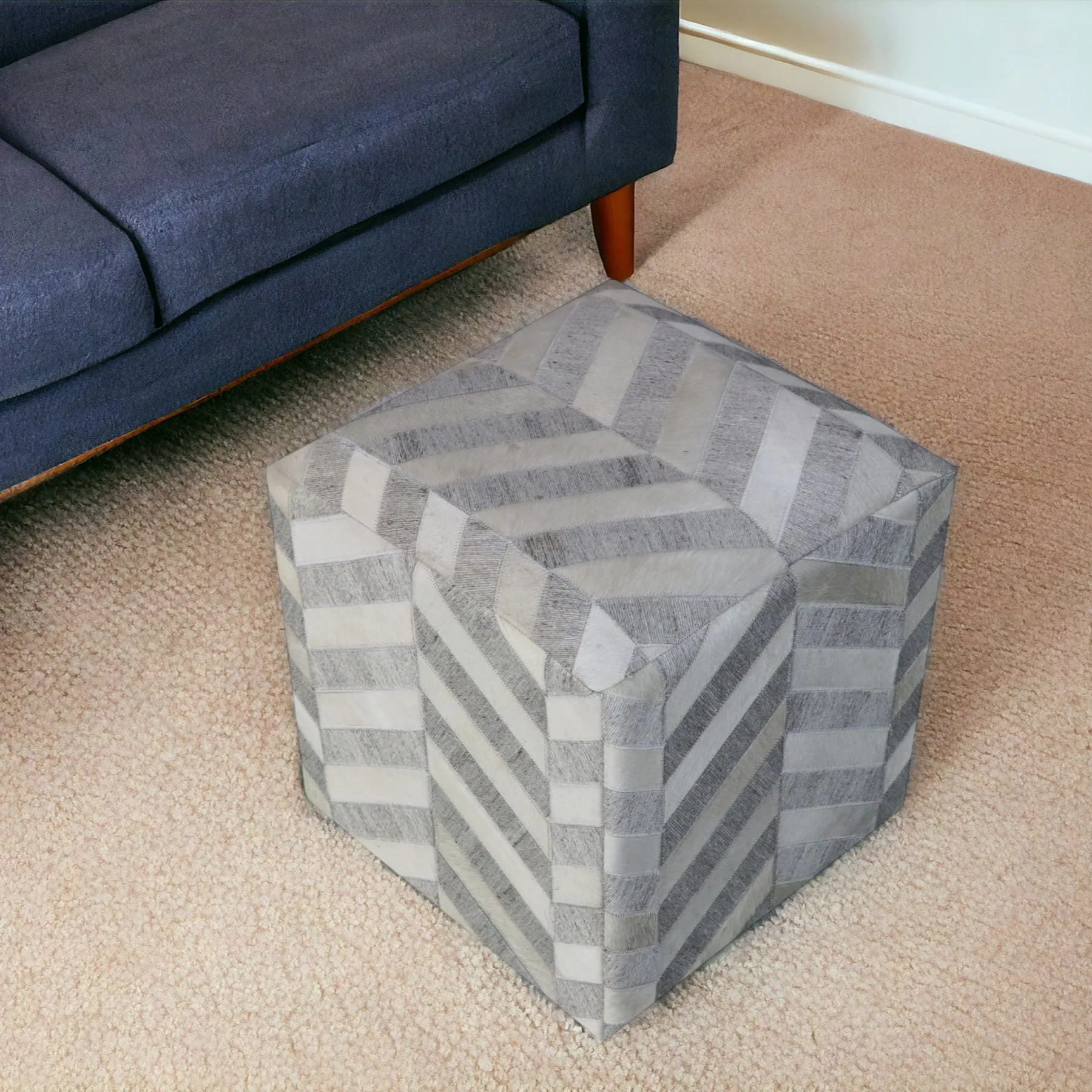 H8763f11102474e7ea13621a5c7a7e52eK.webp Goldoma gray and ivory hair on hide chevron pouf ottoman in a living room setting