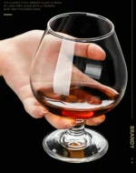 Elegant brandy snifter glass on a wooden table, filled with amber cognac