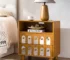 Natural wood nightstand with mirrored front and open shelf in a bedroom