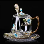 Elegant crystal glass tea mug with enamel floral design and handgrip on a wooden table