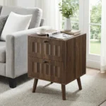 Modern double drawer nightstand with solid wood legs in walnut finish against a bedroom wall
