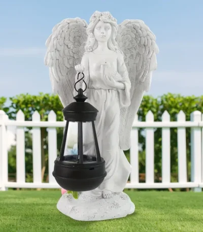 Angel lantern statue glowing in garden at dusk