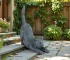 Hand-painted stretching cat statue in garden setting