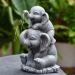 Close-up of resin elephant statue with solar panel on back, glowing warm LED light at dusk, textured gray surface.