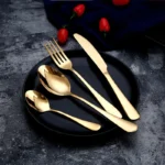 Elegant gold flatware set with fork, knife, and spoon on a white tablecloth