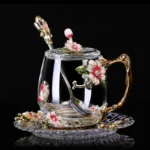 Elegant crystal glass tea mug with enamel floral design and handgrip on a wooden table