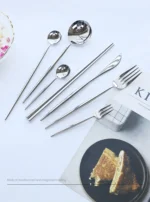 Elegant stainless steel flatware set with forks, spoons, and knives arranged on a wooden table