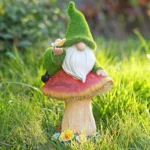 Close-up of resin flocked gnome statue with solar panel on hat, textured gray surface under daylight.