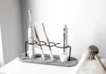 Toothbrush holder with a non-slip base and a cup for toothpaste on a sink edge.