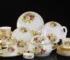 Elegant bone china dinnerware set with plates, bowls, and soup spoons on a wooden table