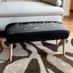 Goldoma gray wool ottoman with brown legs and hidden storage, featuring nailhead trim