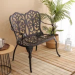 Outdoor metal bench with floral rose design in black finish on a patio