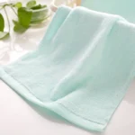 Stack of soft baby bamboo washcloths in pastel colors on a wooden surface