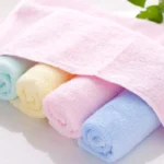 Stack of soft baby bamboo washcloths in pastel colors on a wooden surface