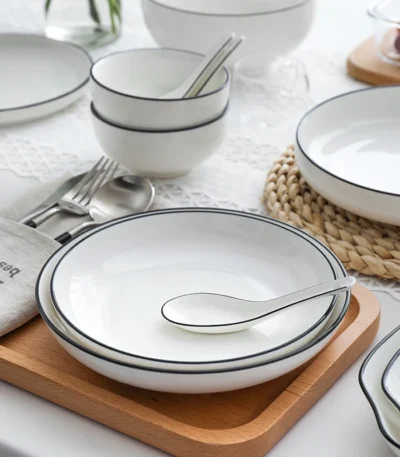 White dinner plate with black rim on a wooden table setting