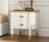 Curved nightstand with drawers featuring feather handles in a modern bedroom setting