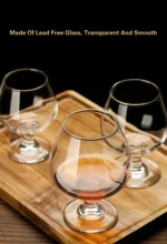 Elegant brandy snifter glass on a wooden table, filled with amber cognac