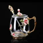 Elegant crystal glass tea mug with enamel floral design and handgrip on a wooden table