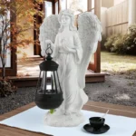 Side view of lighted divine Christmas angel statue on patio, surrounded by greenery.