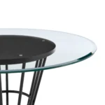 Round glass dining table with black iron pedestal base in a modern dining room setting
