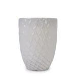 White ceramic planter pot against a brick wall, holding a tall indoor tree in a living room.