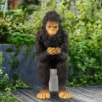 The sasquatch statue on a toilet, positioned on a front porch with potted plants and a wooden railing, under a clear