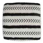 White striped storage ottoman in living room with books and decor on top