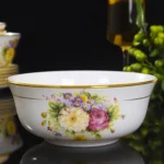 Elegant bone china dinnerware set with plates, bowls, and soup spoons on a wooden table