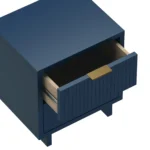 Midnight blue nightstand with wooden legs and gold handles in a cozy bedroom setting