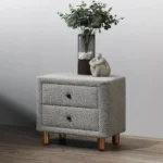 Gray boucle nightstand with two drawers and wooden legs in a modern bedroom setting