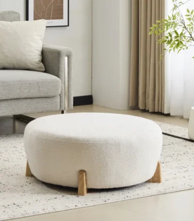 Goldoma white fabric footrest stool with splayed rubber wood legs in a living room near a sofa