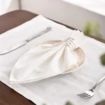Set of 12 white cloth napkins neatly folded on a wooden table