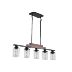 The 5-light pendant light illuminated in a modern farmhouse dining room, casting warm light through the clear glass