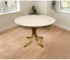 Elegant round marble dining table with ivory marble top and brass pedestal base in a modern dining room