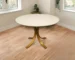 Elegant round marble dining table with ivory marble top and brass pedestal base in a modern dining room